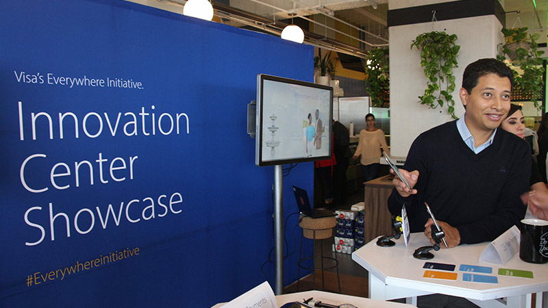Man greets people at the Visa Innovation Center Showcase. 