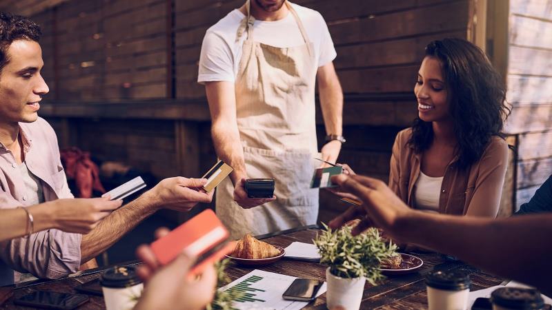 people around table paying contactless